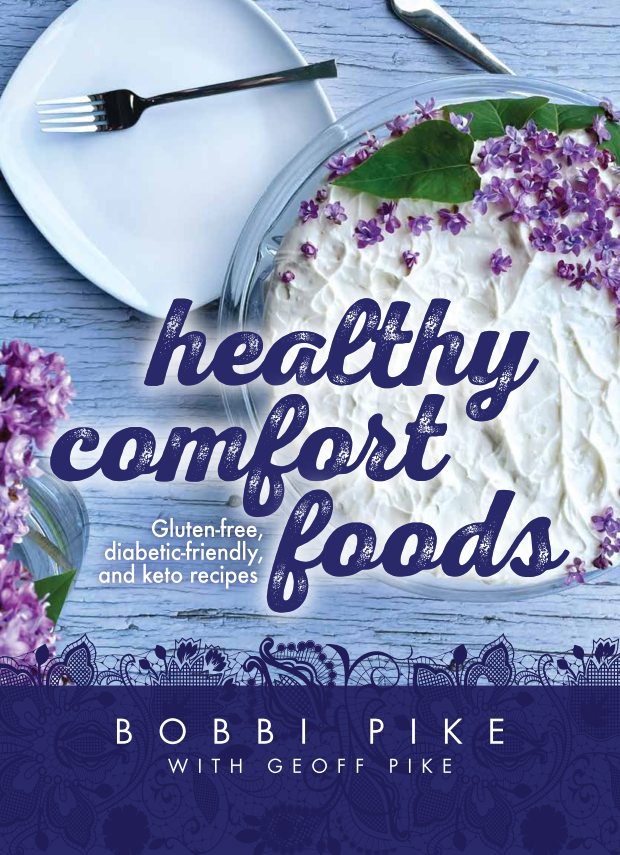 Front cover of Healthy Comfort Foods: GLuten-free, diabetic-friendly, and keto recipes by Bobbi Pike and Geoff Pike. Title text over image of cake with white icing over a blue background.